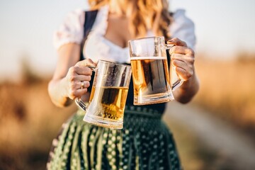 The girl celebrating Oktoberfest with a beer mug in her hand in Germany. Cheerful different foods...