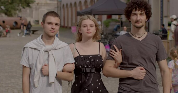 Girl and two guys posing looking at camera. Romantic relationships among three individuals polyamory, involve consensually and openly loving and connecting with multiple partners simultaneously.