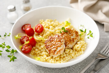 Couscous with chicken patties, cutlets and tomatoes, top down view