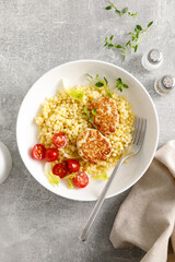 Couscous with chicken patties, cutlets and tomatoes, top down view