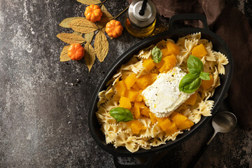 Fetapasta. Baked feta pasta, or Tiktok pasta. Feta pasta recipe made of pumpkins, feta cheese, garlic and herbs on dark stone background. View from above. Copy space.