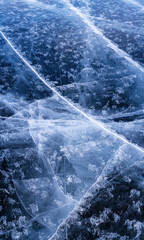 Transparent dark blue ice of frozen Baikal lake with white cracks pattern. Beautiful winter nature background with copy space.