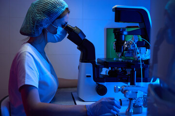 Embryologist in protective gloves and a mask works with biomaterial