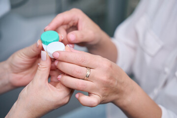 Optician demonstrating plastic container for ophthalmic lenses to client