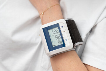 Close-up of wrist blood pressure monitor on female hand measuring pulse and blood pressure. Health care and check up concept