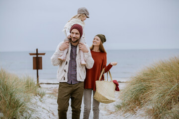 Happy young caucasian couple having fun and walking on a sandy beach during winter