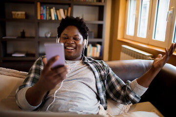 Young African American man receives good news on a smartphone in the living room at home