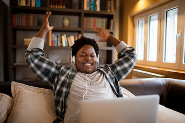 Young African American man receives good news on the laptop in the living room at home