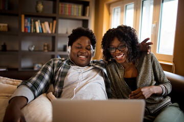 Young African American couple using a laptop on the couch in the living room at home