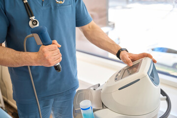General practitioner adjusting extracorporeal shockwave therapy machine