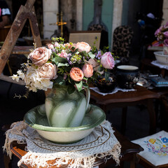 A bouquet of artificial roses, hydrangeas, daisies in a green ceramic jug at a flea market on a...