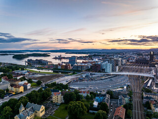Aerial view of railroad infrastructure and modern urban borough in former harbour. Hotels and multistorey apartment houses on waterfront. Metropolis at sunset. Oslo, Norway