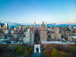 Aerial view of Washington Square Arch and multistorey buildings along 5th avenue at twilight. Tall downtown skyscrapers in background. New York City, USA