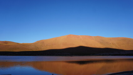 Sunset with orange mountain and mirror of Laguna Machuca in Atacama Chile