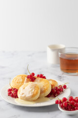 Cottage cheese pancakes, syrniki, ricotta fritters with fresh berries and sour cream on white...