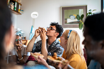 Young and diverse group of friends having a pizza party at home