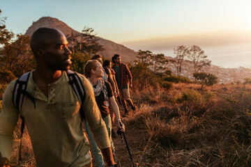 Diverse and young group of friends watching the sunset after conquering a mountain in Africa