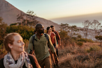 Diverse and young group of friends watching the sunset after conquering a mountain in Africa
