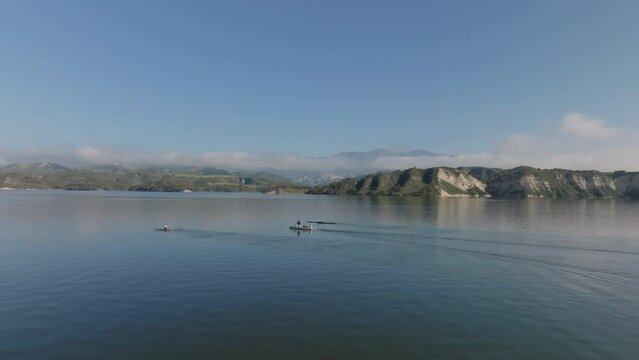 Aerial view of boats of water surface. Two rowing sportsmen and coach on motorboat. Large lake and beautiful nature around. Cachuma Lake, California, USA
