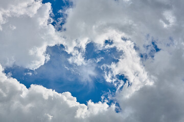 Cumulus clouds against a light blue sky with a clear fiber structure.