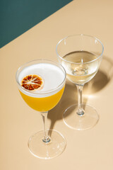 Alcoholic cocktail with foam in two glasses on a colored background.