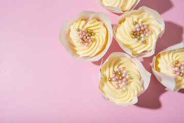Sweet dessert cupcakes with cream and decorating on pink background top view, flat lay. Copy space