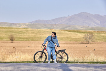Obraz premium A teenage tourist with a bicycle on the background of the highlands in the fresh air