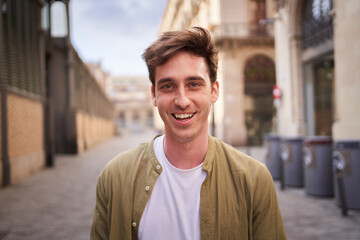 Close up portrait of happy young European man happy smiling face on street. Male people with...