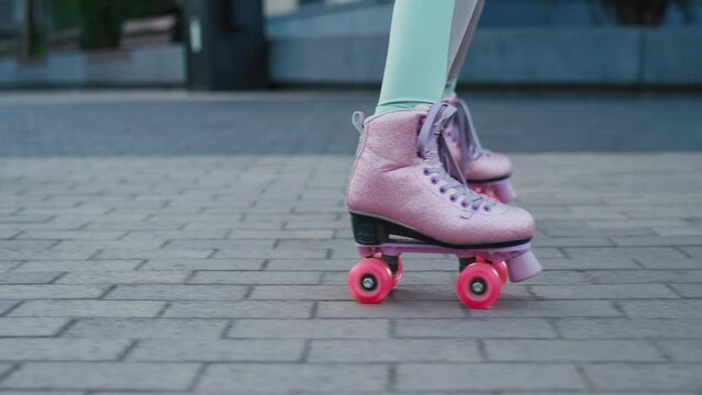 Close up shot of young woman riding quad rollers skates in city. Happy riding retro rollerskates