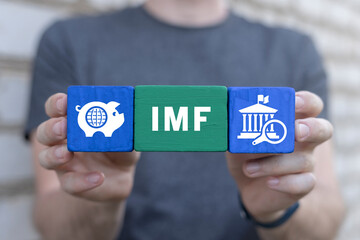 Man holding colorful blocks sees acronym: IMF. IMF International Monetary Fund Concept. International organization that promotes global economic growth and financial stability, international trade.