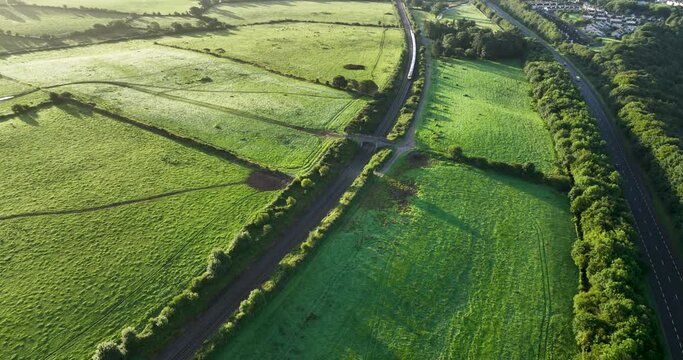 A speeding train passes in front of a picturesque green field 4k