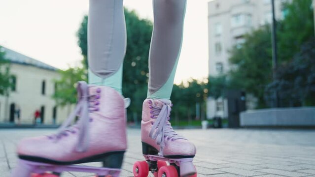 Close up shot of young woman riding quad rollers skates in city. Happy riding retro rollerskates