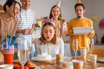 Young woman making wish at birthday party with her friends