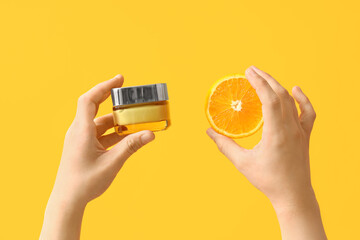 Woman with jar of cream and orange on yellow background - obrazy, fototapety, plakaty