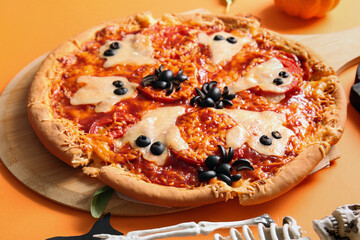 Wooden board with tasty pizza for Halloween celebration on orange background