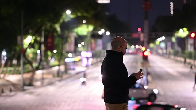 Persona revisando su celular en la calle de noche
