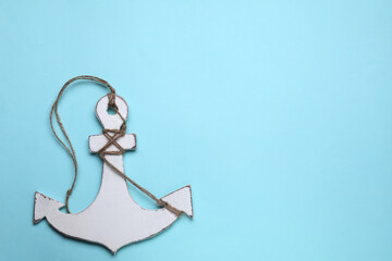White wooden anchor figure on light blue background, top view. Space for text