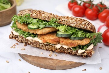 Delicious sandwich with schnitzel on white table