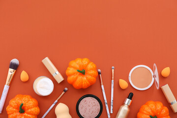 Composition with makeup products and Halloween decor on orange background