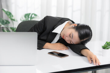Obraz premium Sleepy and tired young Asian businesswoman or female offie worker taking nap or sleep on her office desk.