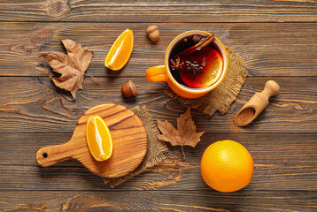 Cup of hot mulled wine with orange and cinnamon on wooden background