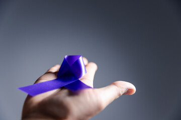 Woman with purple ribbon on palm background, closeup with space for text. Domestic violence...