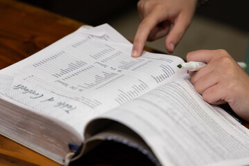 Naklejka premium Woman reading Bible during Bible study time in a discipleship group, hands on pages, pointing to verse while reading, close up of verses on page