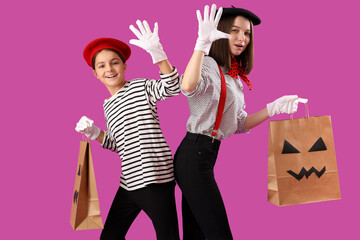 Little girl with her mother dressed for Halloween as mimes with gift bags on purple background - obrazy, fototapety, plakaty