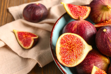 Bowl with ripe fresh figs on brown wooden background