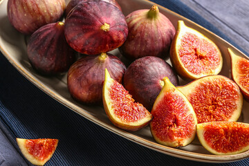 Plate with ripe fresh figs on blue wooden background