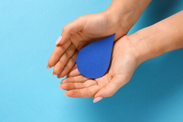 Female hands with paper drop on blue background. World Polio Day