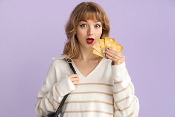Young woman with credit cards on lilac background