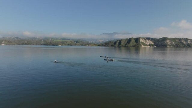 Tracking of athletes training on lake surface. Rowing in beautiful landscape scenery. Cachuma Lake, California, USA