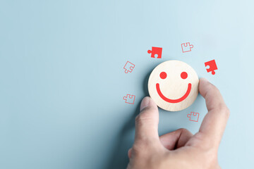 Hands holding blue happy smile face with jigsaw icon. mental health positive solution and growth mindset, mental health care recovery to happiness emotion. - obrazy, fototapety, plakaty